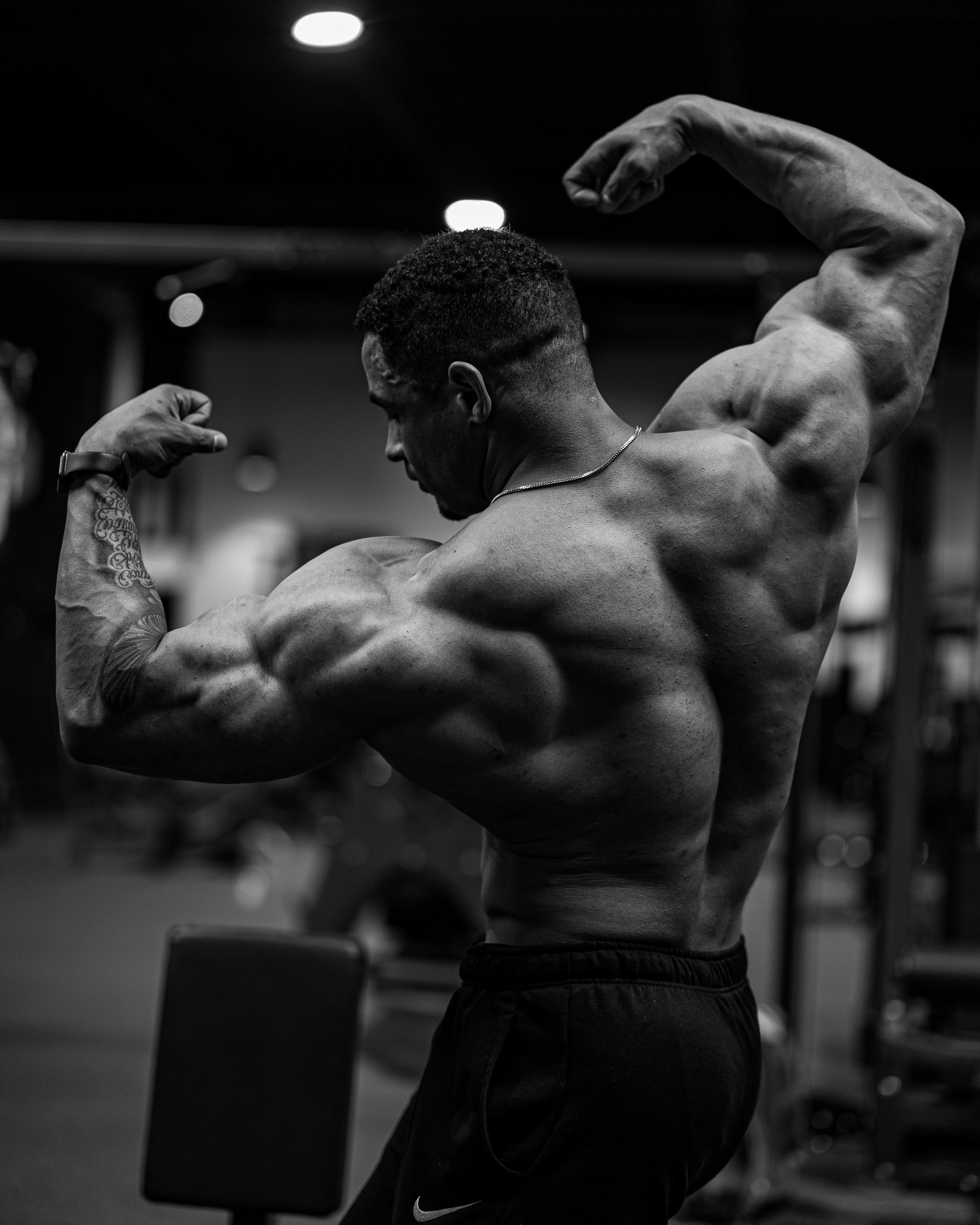 Black and white photo of a bodybuilder flexing muscles indoors.